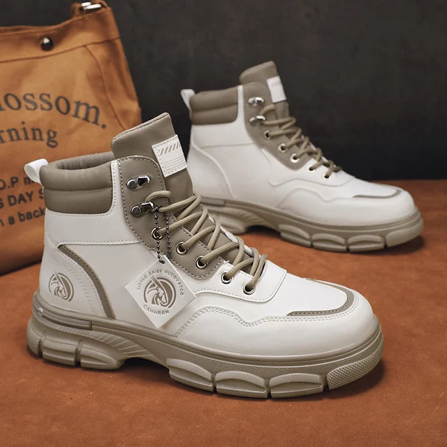 A pair of sleek black leather ankle boots with rugged rubber soles, lace-up fronts, and metal eyelets, displayed on a gray fabric surface with one boot propped up on a vintage-style book for presentation.