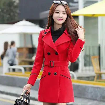 A woman wearing red top coat and holding a black bag.