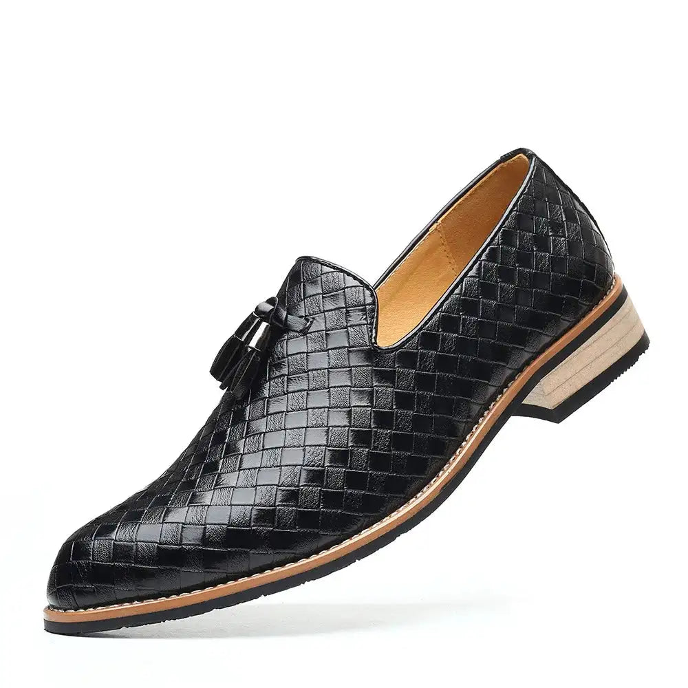 A stylish navy blue woven leather loafer with tassel accents, featuring a light tan interior and a stacked sole with a black rubber outsole, displayed against a white background.