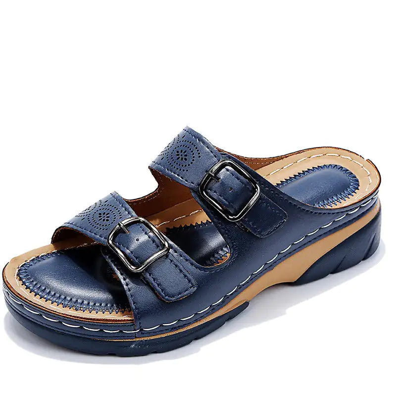 Navy blue slip-on wedge sandal with two adjustable buckle straps, stitched detailing, and an open toe, shown on a white background.