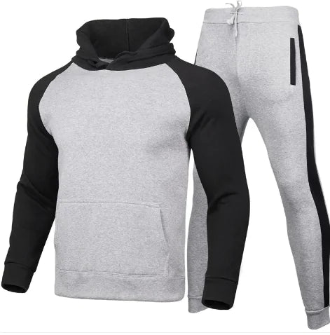 A stylish two-piece men's tracksuit. The set includes a hooded sweatshirt with a kangaroo pocket and long gray sleeves, along with matching jogger pants that have a drawstring waist and gray side panels with zippered pockets. The design offers a sporty yet casual look, ideal for workouts or everyday wear.