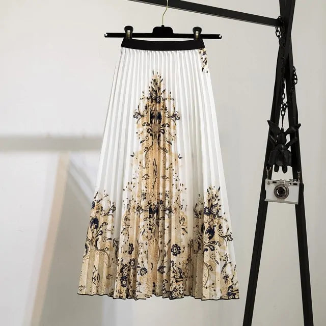 Pleated midi skirt with a gradient design, transitioning from dark black at the waistband to a soft blush pink at the hem, hanging on a black clothing rack next to a vintage-style camera.