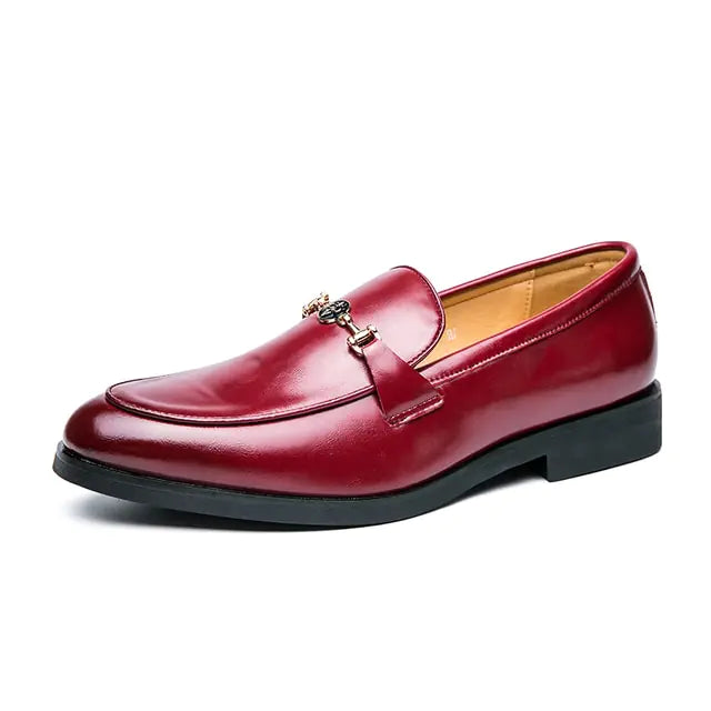 A sleek leather men's loafer with a low heel and metal buckle detail on the upper, displayed against a white background.