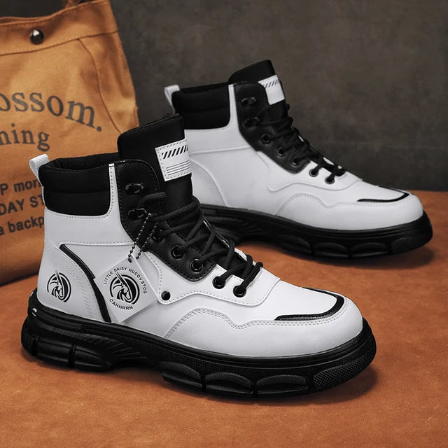 A pair of sleek black leather ankle boots with rugged rubber soles, lace-up fronts, and metal eyelets, displayed on a gray fabric surface with one boot propped up on a vintage-style book for presentation.