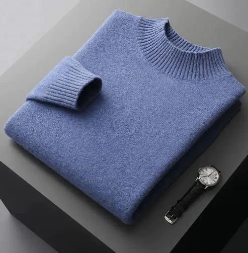 A neatly folded beige knitted sweater with a ribbed high collar and cuffs, placed on a dark grey surface. Beside the sweater, a classic wristwatch with a black leather strap and a silver dial is positioned, adding a touch of elegance to the composition.