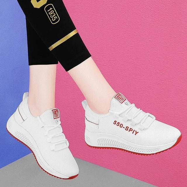 A pair of stylish mesh sneakers worn with jeans. The shoes feature colorful embroidered details The sneakers have a sleek, breathable design and a casual, trendy aesthetic.