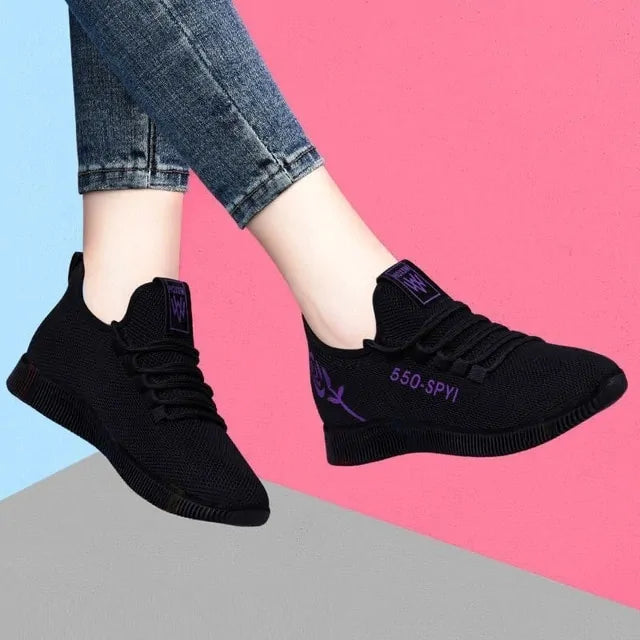 A pair of stylish mesh sneakers worn with jeans. The shoes feature colorful embroidered details The sneakers have a sleek, breathable design and a casual, trendy aesthetic.