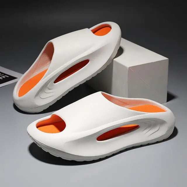 A pair of stylish black slip-on sandals with purple cushioned insoles, featuring cutout designs on the sides and toes, displayed on a white surface next to stacked books.