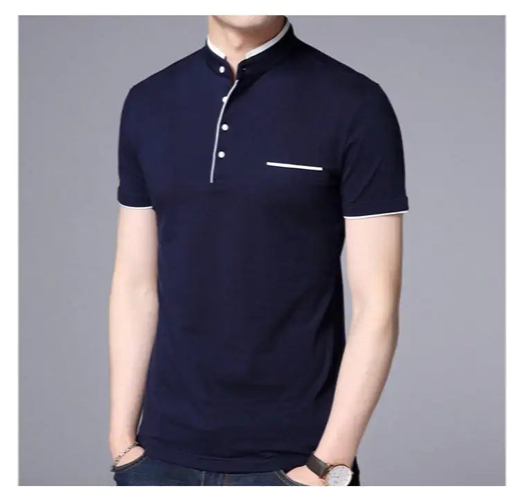 A stylish short-sleeved polo shirt with a mandarin collar, white trim detailing, and a partial button-up design. The shirt features a small decorative white-lined pocket on the left chest. The model is wearing dark jeans, a brown leather belt, a wristwatch, and a bracelet, posing casually with one hand resting on the belt buckle