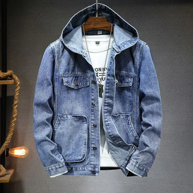 A stylish denim jacket with a hood, layered over a white graphic t-shirt and accessorized with a silver pendant necklace. The jacket features a button-up front, multiple pockets, and a slightly distressed finish, giving it a rugged yet fashionable look. The hoodie detail adds a modern, casual touch, making it perfect for streetwear or casual outings.