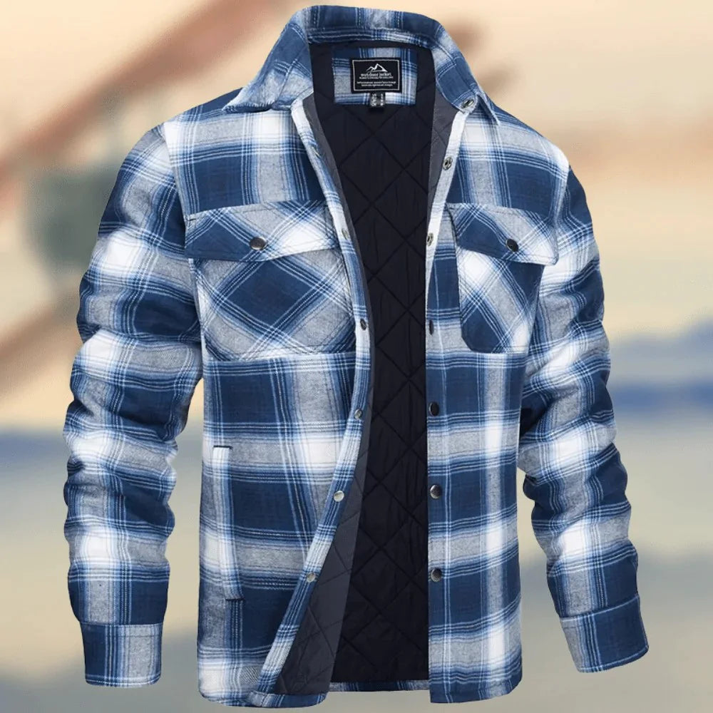 A dark brown men's pullover sweater with a textured cable knit pattern on the front. The sweater features a high ribbed collar with tan brown buttoned detailing, ribbed cuffs and hem, and matching tan elbow patches. The background consists of distressed, multicolored metal panels.