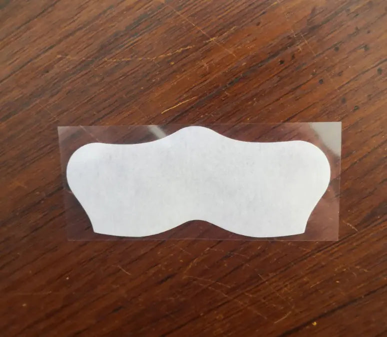White adhesive patch on a clear backing on a wooden surface