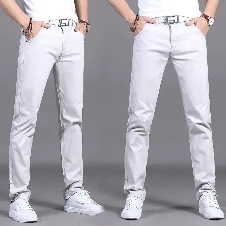 A pair of slim-fit burgundy pants is showcased by a model in two poses against a neutral gray background. The pants are paired with a white belt featuring a bold black buckle design, a white tucked-in shirt, and white sneakers. The model wears a wristwatch and bracelets, adding a stylish touch. The pants have a sleek, modern fit, emphasizing a trendy and casual yet polished look.