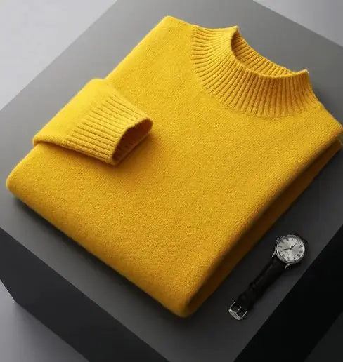 A neatly folded beige knitted sweater with a ribbed high collar and cuffs, placed on a dark grey surface. Beside the sweater, a classic wristwatch with a black leather strap and a silver dial is positioned, adding a touch of elegance to the composition.