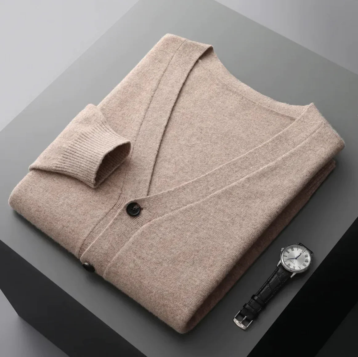 A neatly fold shirt on a black box with a black leather watch beside it
