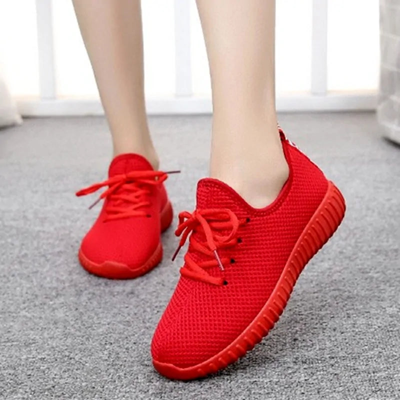 A pair of stylish mesh sneakers worn with jeans. The shoes feature colorful embroidered details The sneakers have a sleek, breathable design and a casual, trendy aesthetic.