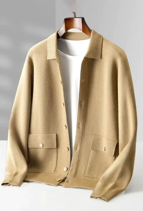 A beige button-up knit cardigan with a relaxed fit, featuring a classic collar, two front pockets with buttoned flaps, and ribbed cuffs and hem. The cardigan is layered over a white T-shirt and displayed on a wooden hanger, exuding a casual yet refined aesthetic.