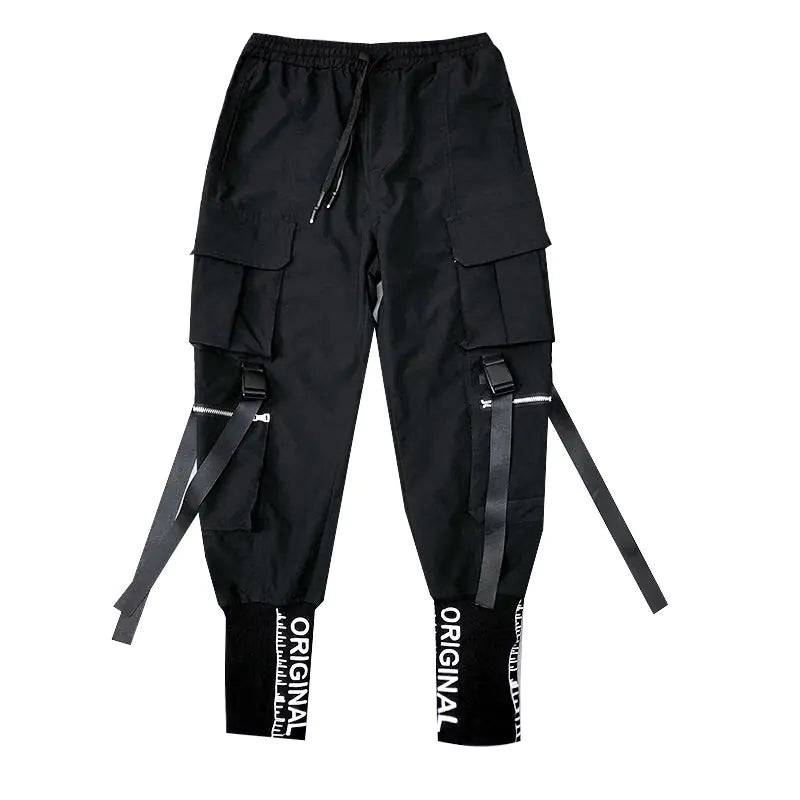 A pair of black cargo jogger pants with multiple pockets, adjustable straps, and a streetwear-inspired design. The pants feature large flap pockets on both thighs, decorative zippers, and hanging black straps attached to silver buckles. The elasticized cuffs have bold white text reading "ORIGINAL" along with a barcode-like design, adding to the urban aesthetic. The pants also have an elastic waistband with a drawstring for a comfortable fit.