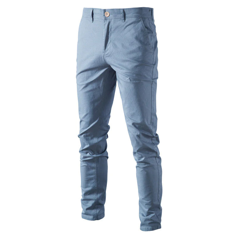 A pair of slim-fit navy blue men's trousers made from a smooth fabric. The pants feature a button and zipper closure, belt loops, and side pockets. The tailored design gives them a sleek and modern look, suitable for both casual and semi-formal occasions.