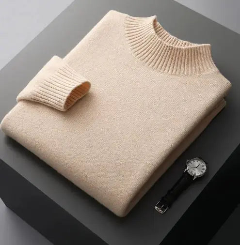 A neatly folded beige knitted sweater with a ribbed high collar and cuffs, placed on a dark grey surface. Beside the sweater, a classic wristwatch with a black leather strap and a silver dial is positioned, adding a touch of elegance to the composition.