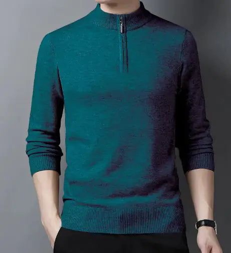 A fashionable teal-colored slim-fit sweater with a quarter-zip collar, worn by a male model against a neutral gray background. The sweater features ribbed cuffs and a ribbed hem for a snug fit. The model pairs it with black trousers and a silver wristwatch, creating a refined and modern look