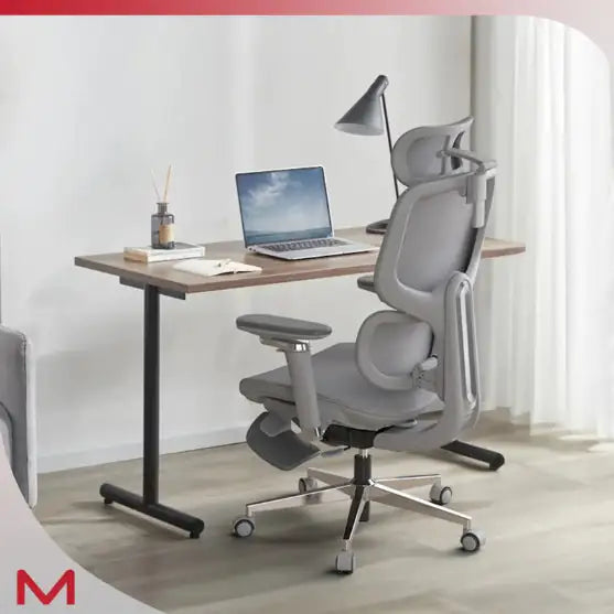 Ergonomic office chair in front of a desk with a laptop and lamp in a bright room.