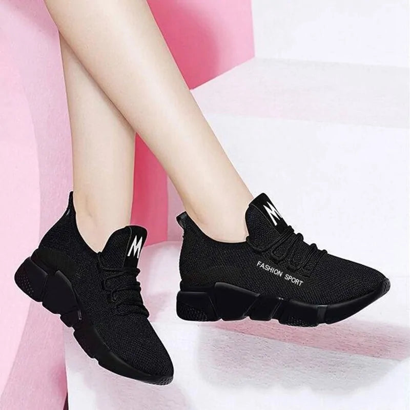 A pair of stylish mesh sneakers worn with jeans. The shoes feature colorful embroidered details The sneakers have a sleek, breathable design and a casual, trendy aesthetic.