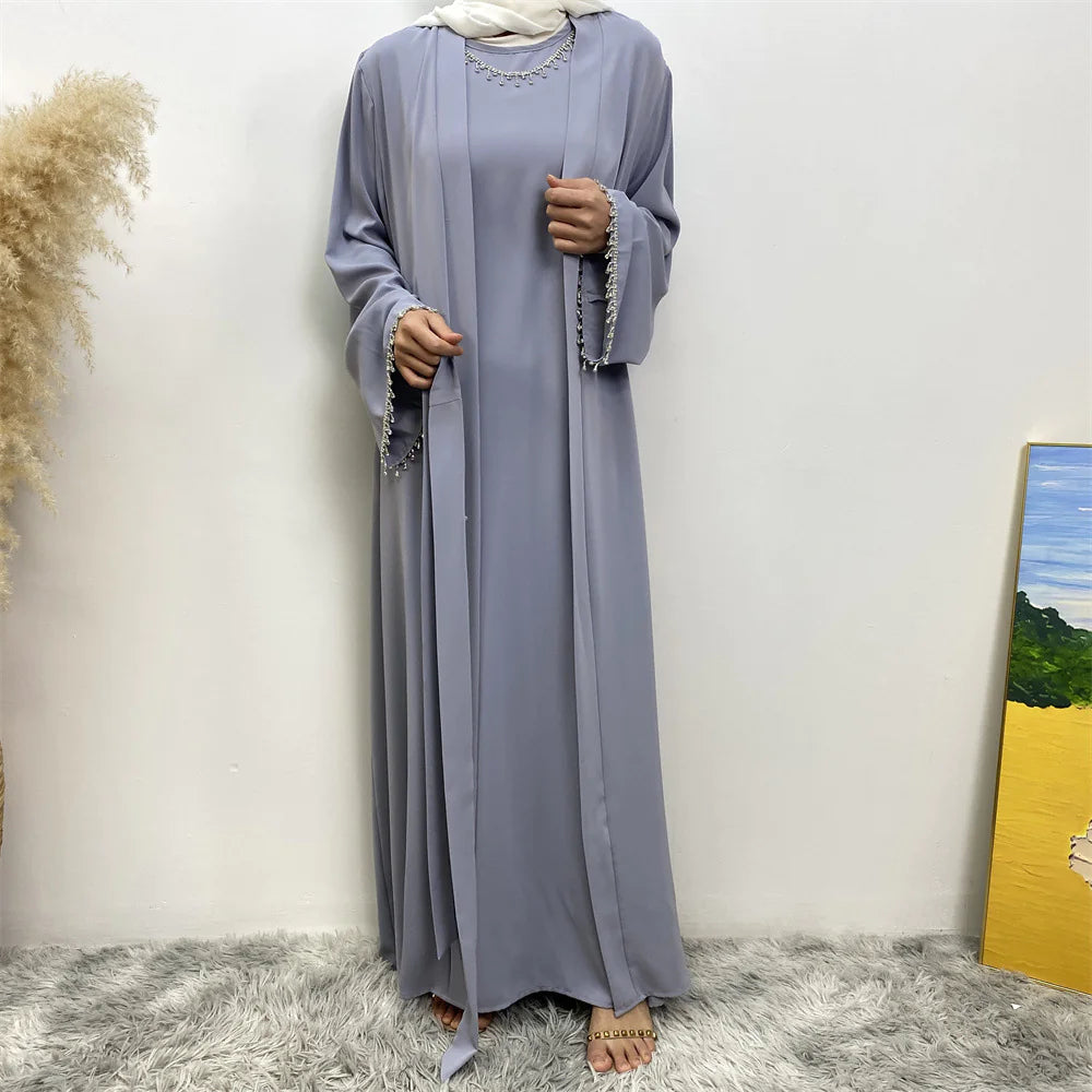 Woman wearing a loose-fitting, white midi dress with short sleeves, featuring bold red-orange floral prints accented with blue centers, paired with flat sandals.