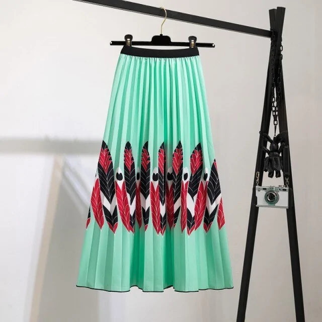 Pleated midi skirt with a gradient design, transitioning from dark black at the waistband to a soft blush pink at the hem, hanging on a black clothing rack next to a vintage-style camera.