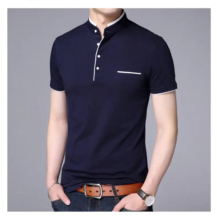 A stylish short-sleeved polo shirt with a mandarin collar, white trim detailing, and a partial button-up design. The shirt features a small decorative white-lined pocket on the left chest. The model is wearing dark jeans, a brown leather belt, a wristwatch, and a bracelet, posing casually with one hand resting on the belt buckle