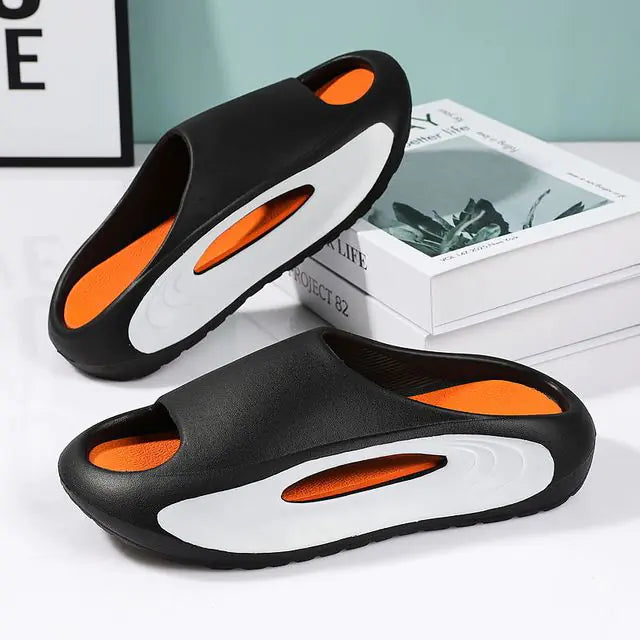 A pair of stylish black slip-on sandals with purple cushioned insoles, featuring cutout designs on the sides and toes, displayed on a white surface next to stacked books.