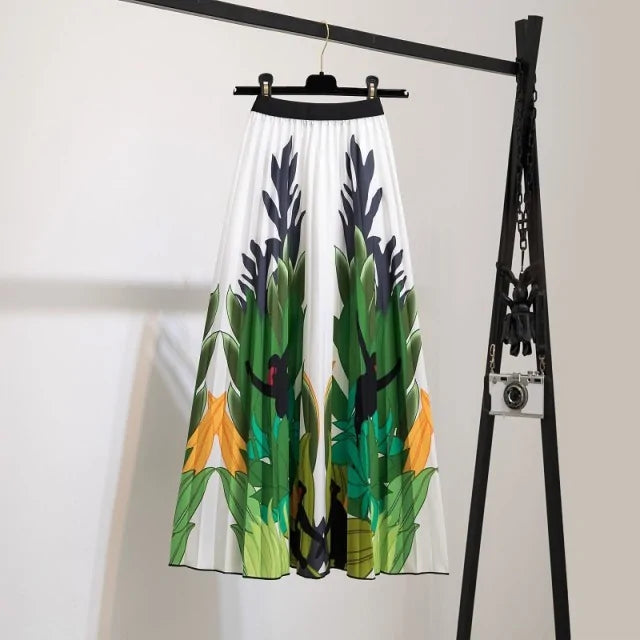 Pleated midi skirt with a gradient design, transitioning from dark black at the waistband to a soft blush pink at the hem, hanging on a black clothing rack next to a vintage-style camera.