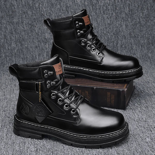 A pair of sleek black leather ankle boots with rugged rubber soles, lace-up fronts, and metal eyelets, displayed on a gray fabric surface with one boot propped up on a vintage-style book for presentation.