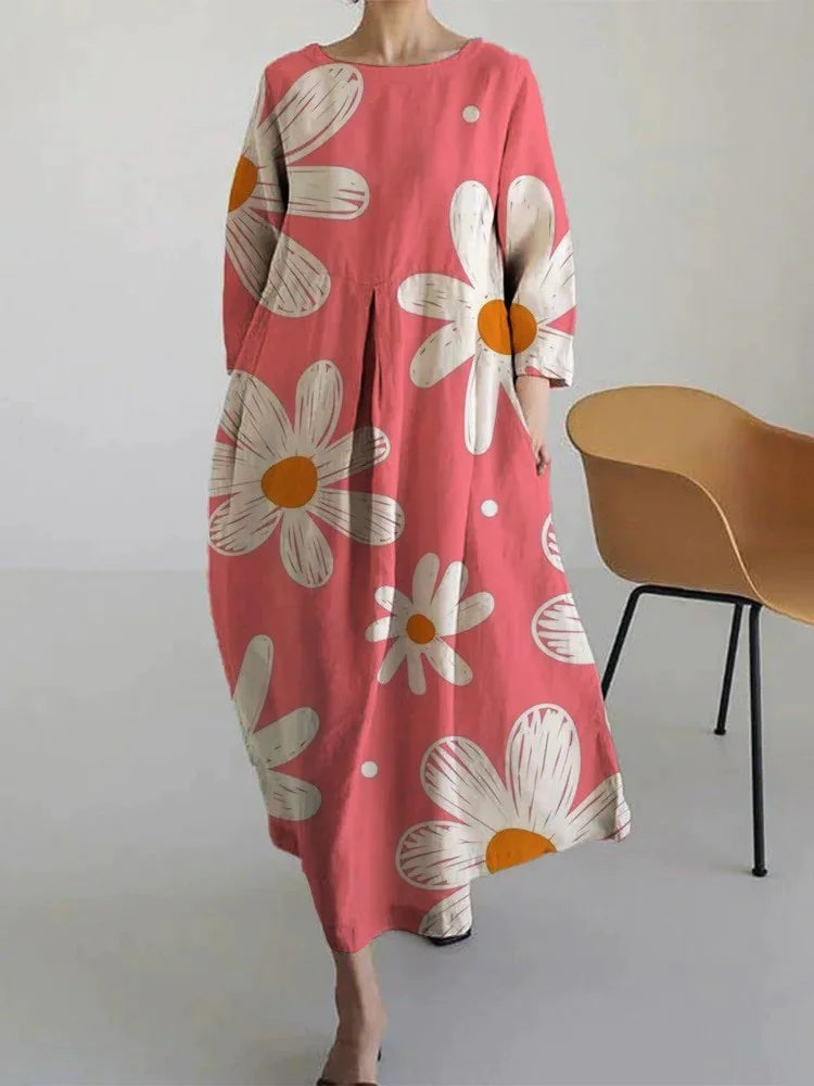 Woman wearing a loose-fitting, white midi dress with short sleeves, featuring bold red-orange floral prints accented with blue centers, paired with flat sandals.