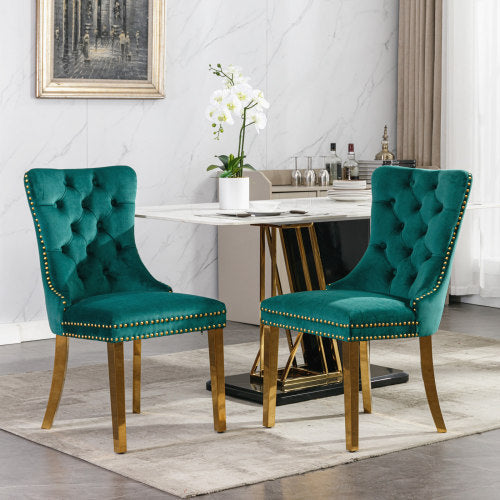 Two teal tufted chairs with gold nailheads in a dining room setting.