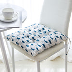 Chair with a blue whale patterned cushion, next to a white table with a cup and saucer.
