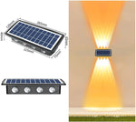 Solar-powered outdoor wall light shown in a product collage: a rectangular solar panel lamp with four LED lenses (dimensions labeled) and an example of the light installed on a wall casting wide up-and-down warm beams.