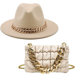 Cream fedora hat and matching ruched mini handbag set with chunky gold chain accents.
