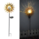 Two-panel product image of a solar garden stake light shaped like a gold sun with a round center; left panel shows the full stake with attached solar panel, right panel shows it lit at night casting patterned rays on a wall above a small fence.