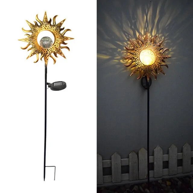 Two-panel product image of a solar garden stake light shaped like a gold sun with a round center; left panel shows the full stake with attached solar panel, right panel shows it lit at night casting patterned rays on a wall above a small fence.
