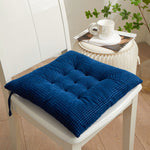 Blue cushion on a chair with a white table and plant in the background