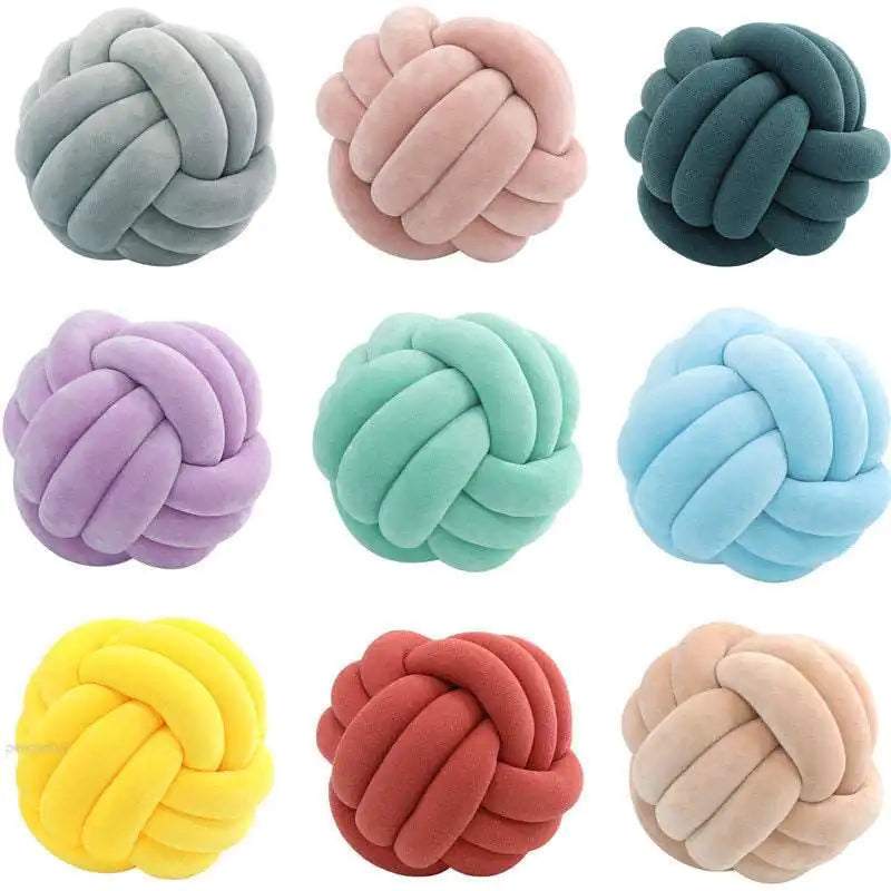 Grid of nine knotted ball cushions in different colors—gray, pink, teal, lavender, mint, light blue, yellow, red, and beige—shown on a white background.