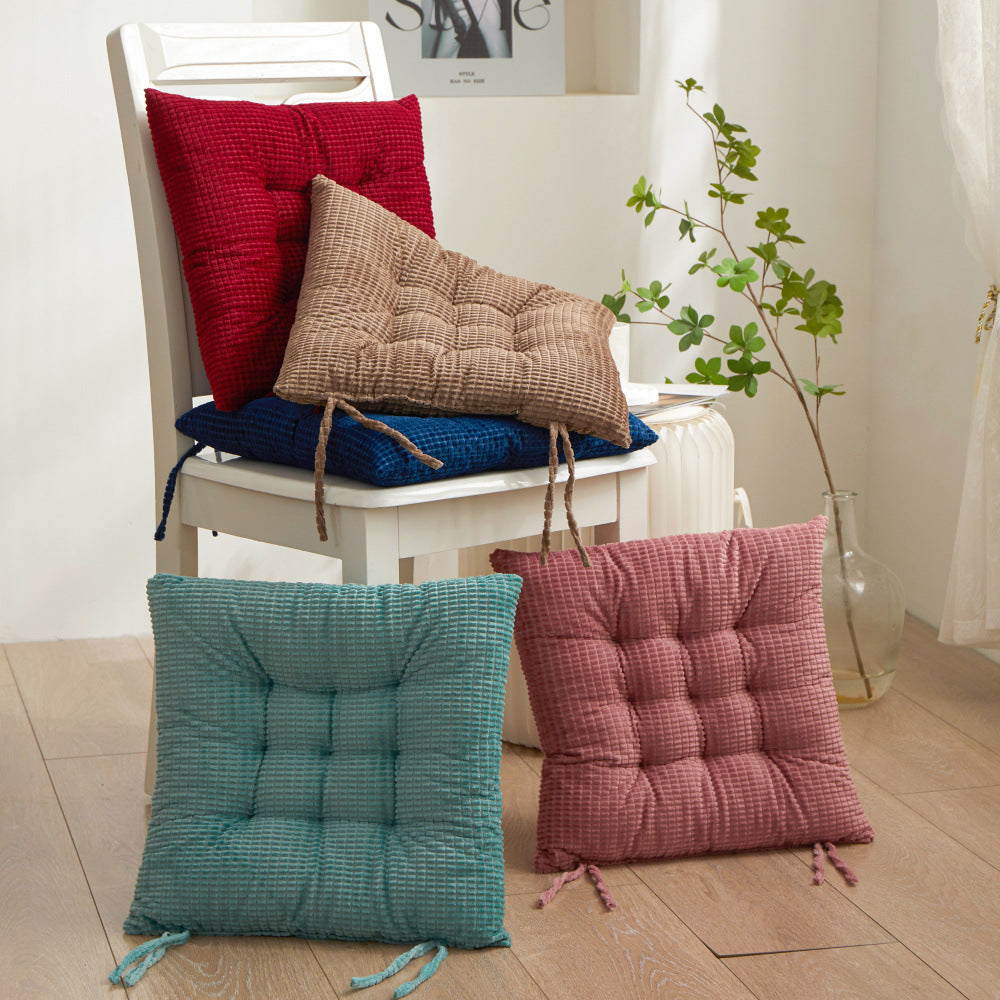 Colorful chair cushions on a white chair and floor in a room with plants.