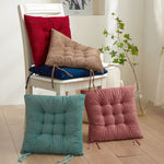 Colorful chair cushions on a white chair and floor in a room with plants.