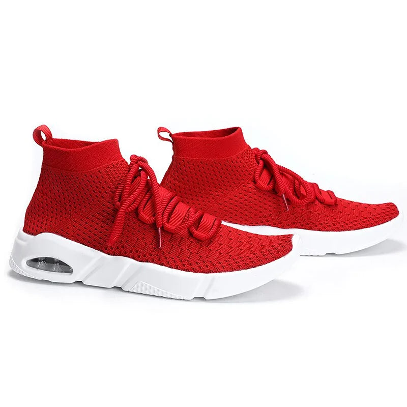 Red sock-style knit trainers with a lace-up front, breathable mesh upper, heel pull tab, and chunky white sole with visible air cushioning.
