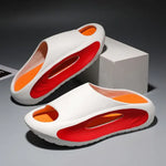 A pair of stylish black slip-on sandals with purple cushioned insoles, featuring cutout designs on the sides and toes, displayed on a white surface next to stacked books.