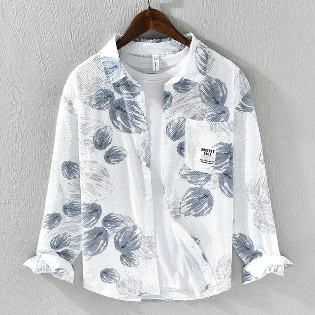 This is a stylish long-sleeve button-up shirt with a white base and an artistic abstract print in gray tones. The lightweight, textured fabric gives it a breezy, casual feel, making it perfect for layering over a t-shirt, as shown in the image. It also features a front pocket with a small label detail that adds a modern touch.