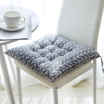 Gray leaf-patterned cushion on a white chair with a blurred background