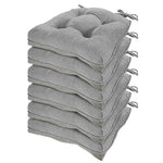 Stack of gray cushion pads with tassels on a white background