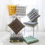 Collection of patterned cushions on chairs and a table in a bright room.